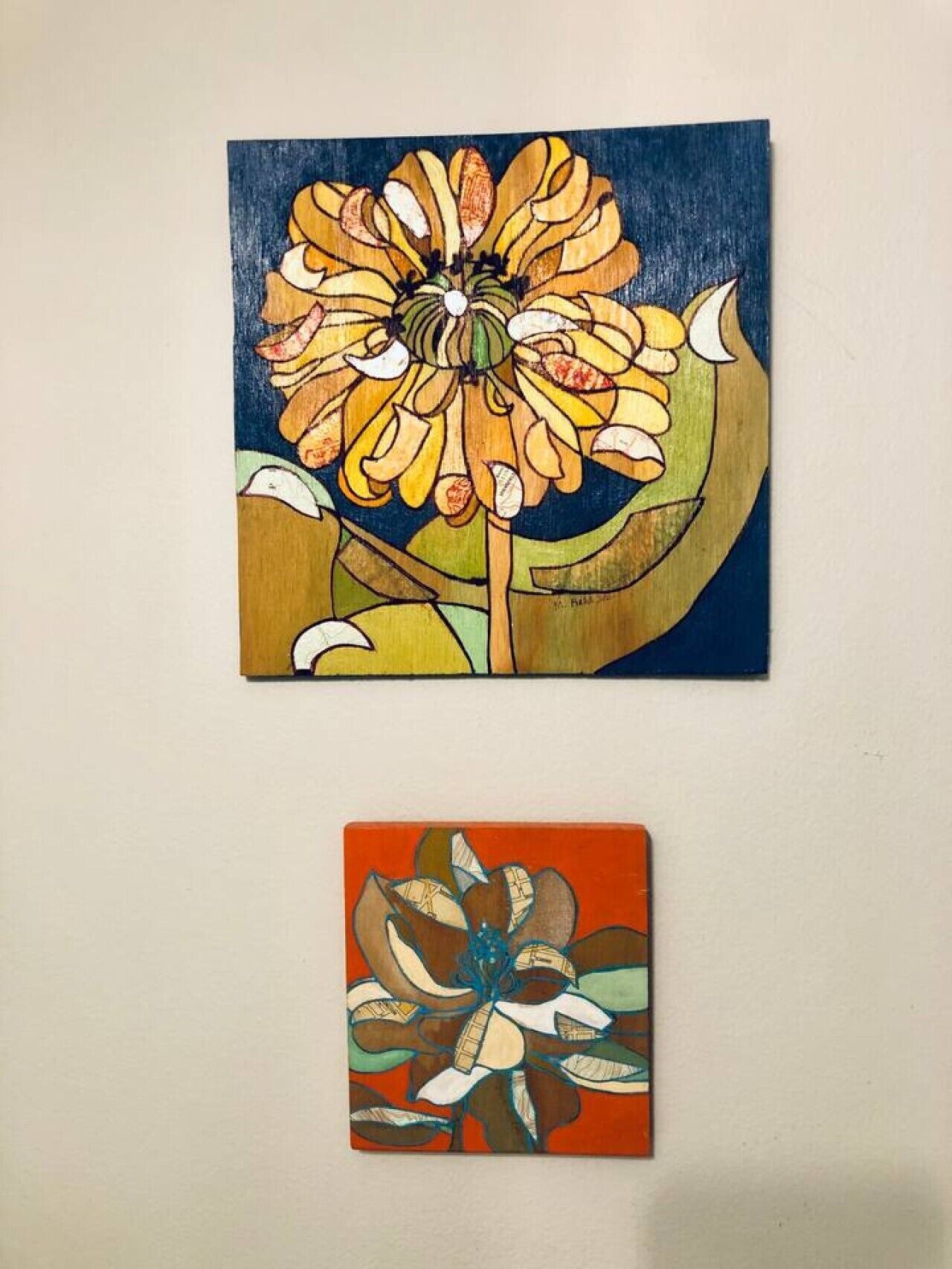 Dos cuadros de flores, uno más grande y otro más pequeño, sobre un fondo liso.