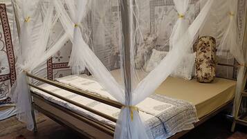 Una cama con dosel y cuatro columnas, con cubrecama blanco y almohada decorativa.