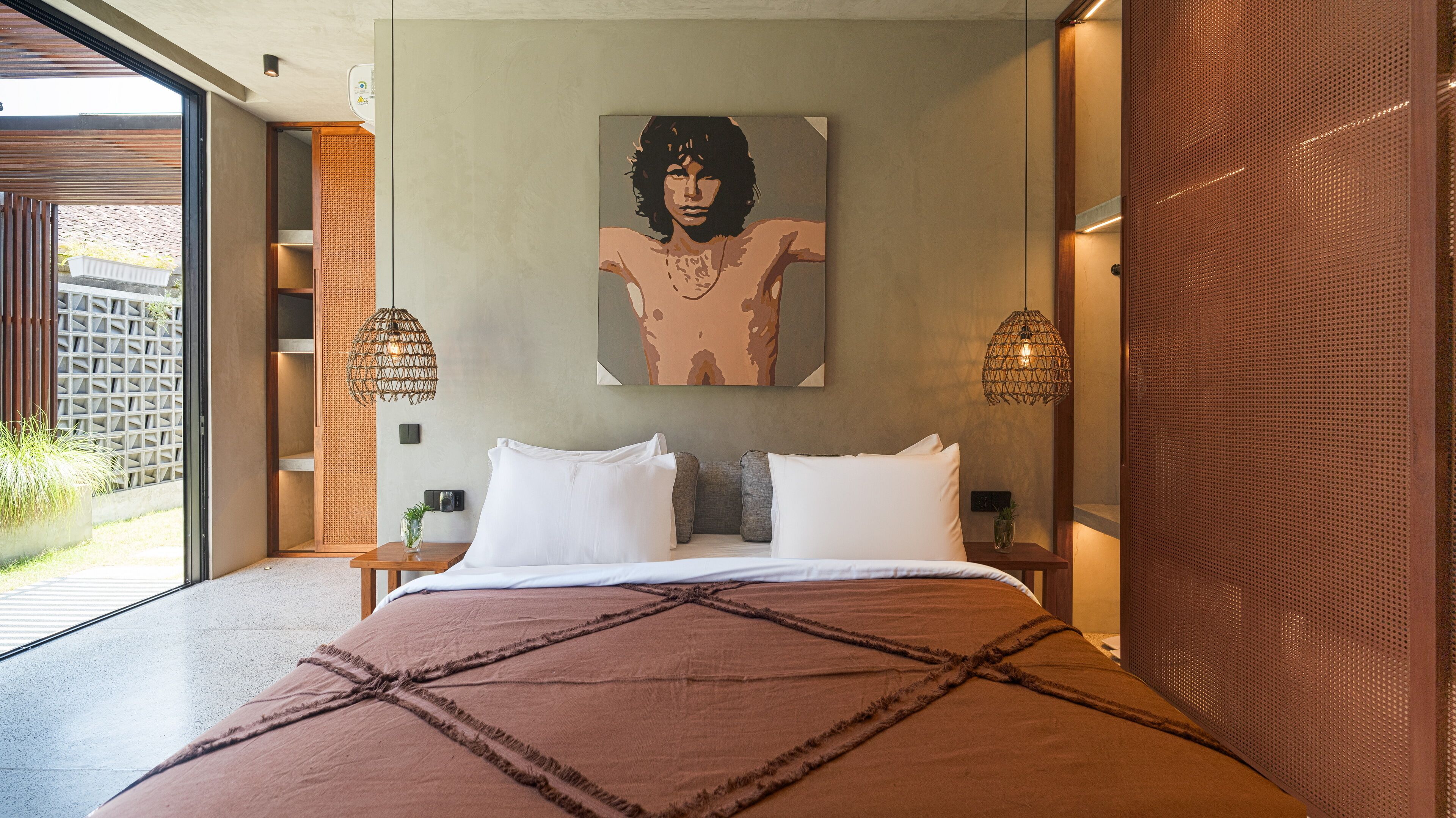 A modern bedroom with a large bed, two bedside tables, a wall-mounted painting, and a woven pendant light.