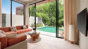 A modern living room with a large window, a pool, and a flat-screen TV. - Garden Villa Ubud By BREIG (Ubud)