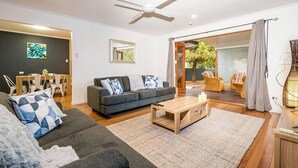 A modern living room with a sofa, coffee table, and a dining area with chairs and a table.