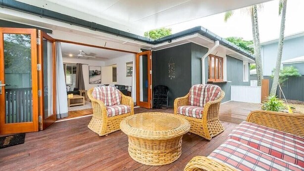 A covered outdoor area with wicker furniture, a round table, and a sofa.