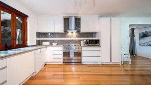 A modern kitchen with white cabinets, a stainless steel stove, and a microwave.
