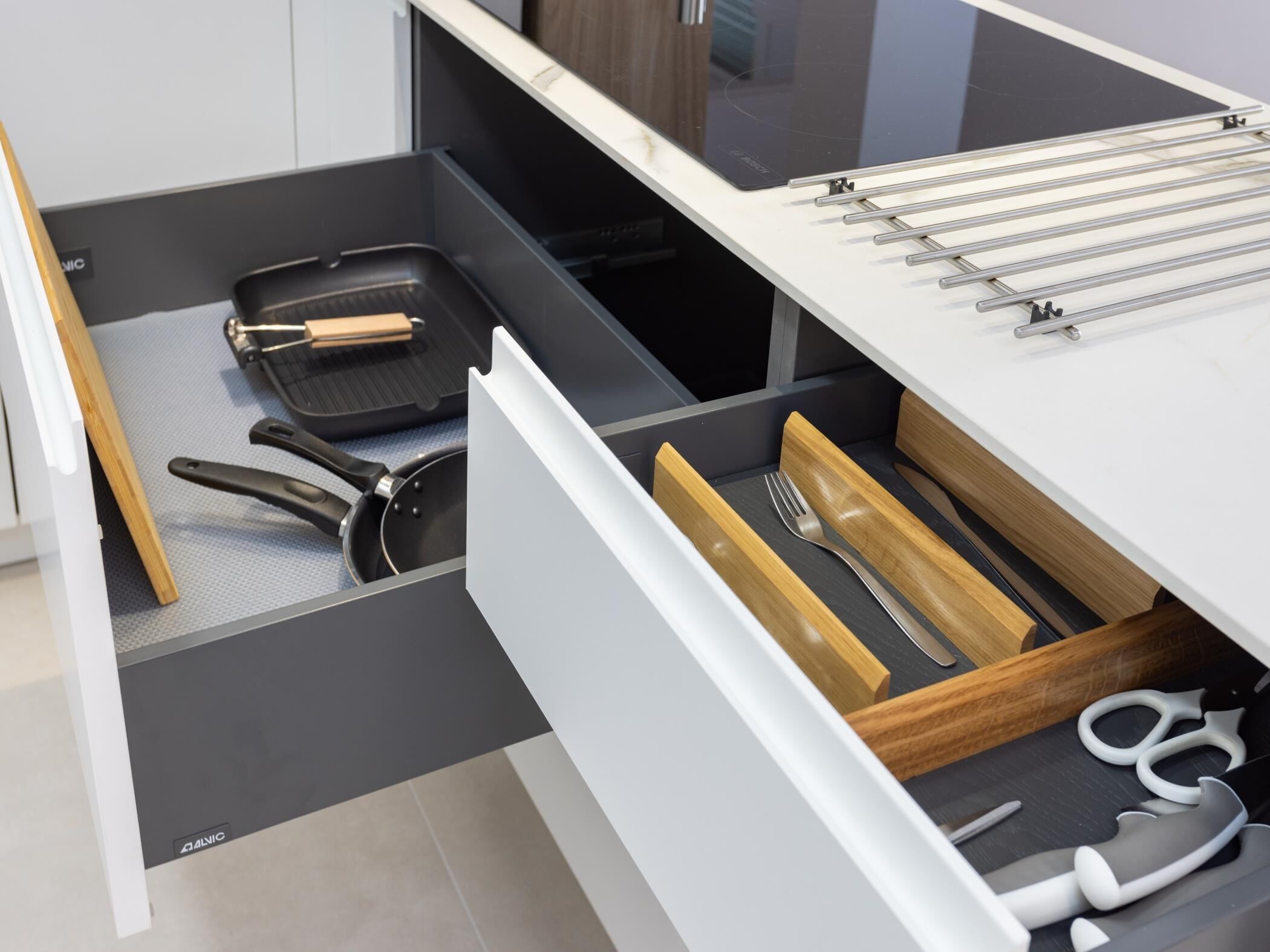 A kitchen drawer with a frying pan, spatula, and utensils.