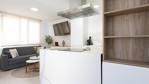 Uma cozinha moderna com fogão embutido, televisão de tela plana e prateleiras de madeira.