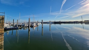 Een jachthaven met aangemeerde boten, kalm water en heldere lucht.