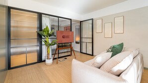 Un salon moderne avec une porte-fenêtre coulissante, une plante en pot, un canapé et une pancarte indiquant « PRÊT POUR LES INVITÉS ».