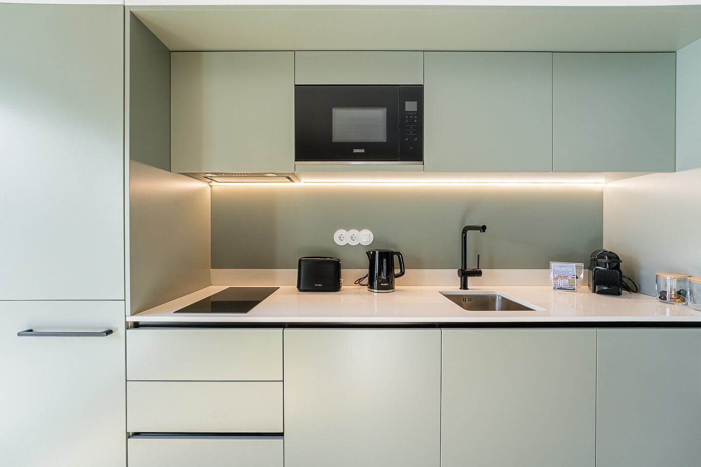 Una cocina moderna con microondas integrado, cafetera y hervidor sobre la encimera.