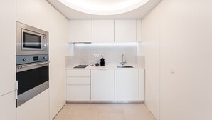 A compact kitchen with a built-in oven, microwave, and coffee maker. - GuestReady - Modern ambience in Porto (Porto)