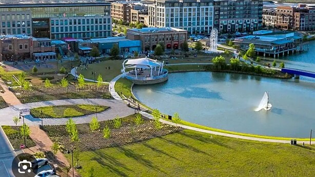 An aerial view of a cityscape with a central park area, a fountain, and modern buildings. - Lovely 4-bedroom house in charming Irving with AC, WiFi - Coppell Schools. (Irving)