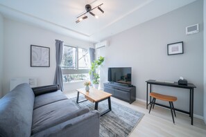A modern living room with a grey sofa, a wooden coffee table, a TV, a desk, and a plant. - ALTIPLANO (Sapporo)