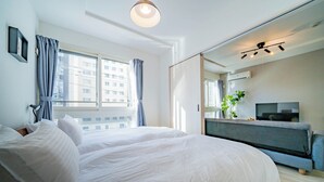 A modern hotel room with a large bed, a TV, and a view of the city through the window. - ALTIPLANO (Sapporo)