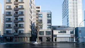 A multi-story building with a modern architectural design, featuring balconies and large windows. - ALTIPLANO (Sapporo)
