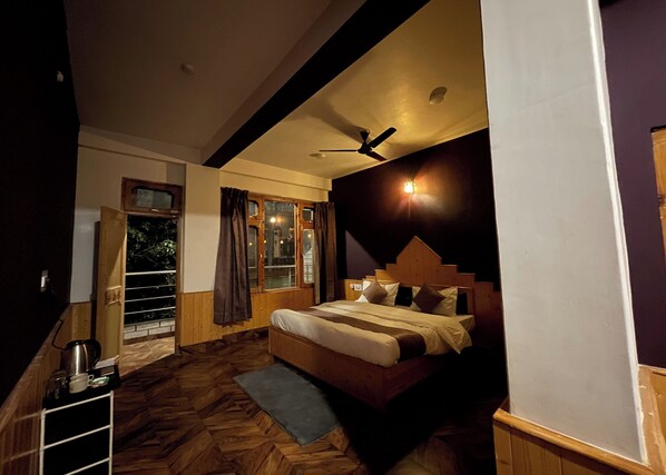 Un dormitorio con cabecera de madera, una cama con almohadas, un ventilador de techo y una ventana con cortinas.