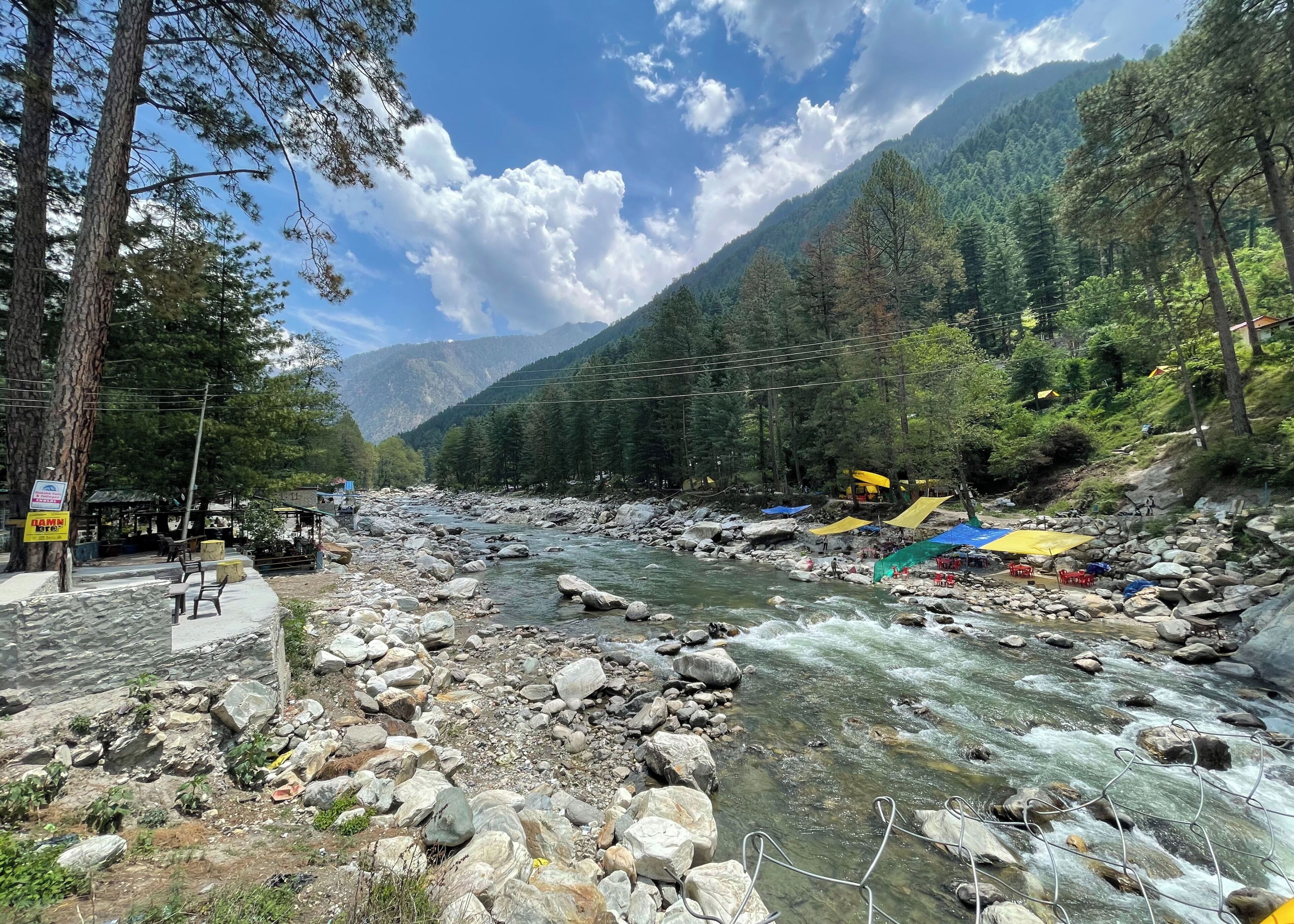 A river with rocks and a few chairs along the bank.
