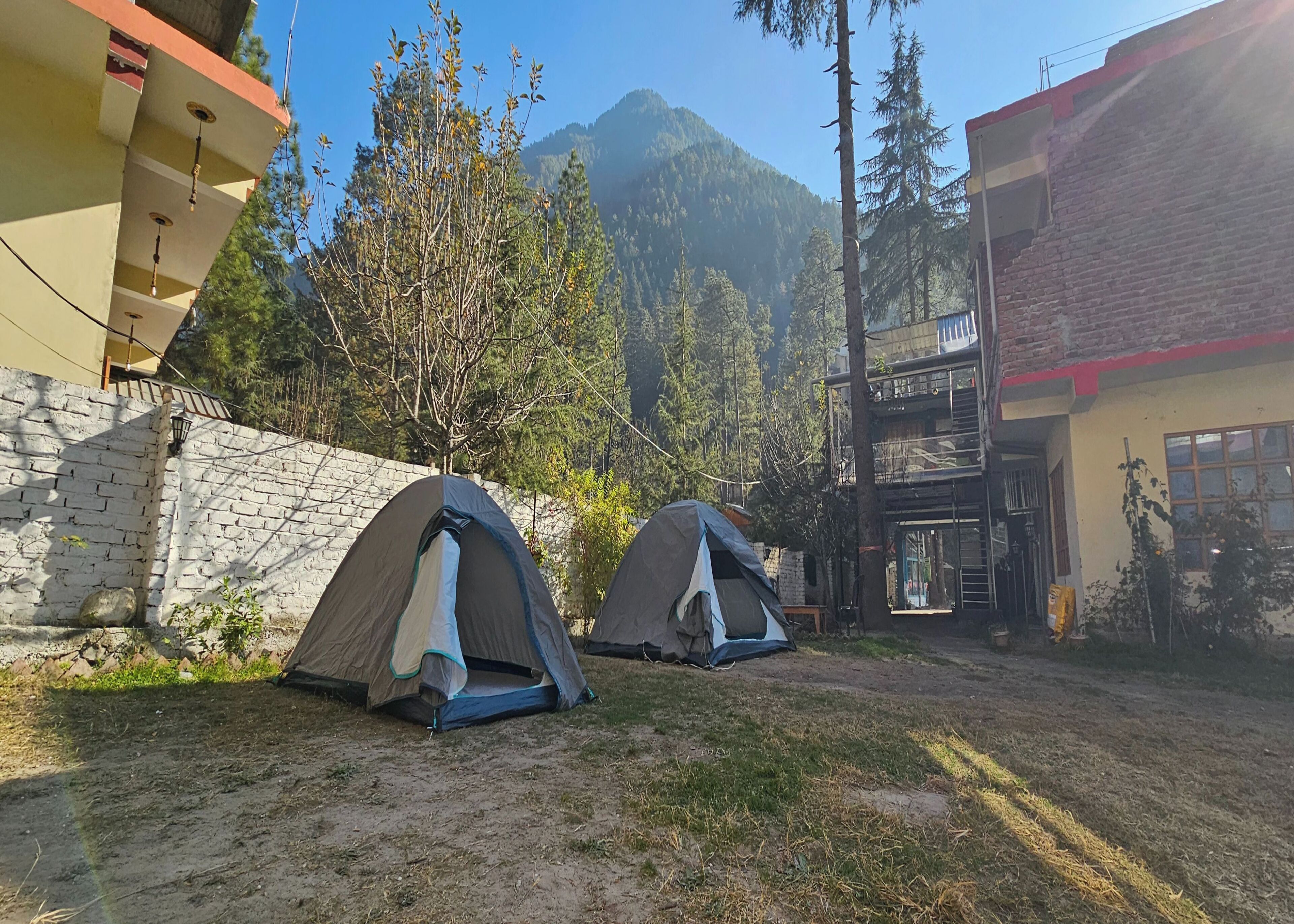 Dos tiendas de campaña montadas en una zona cubierta de césped con una montaña al fondo.