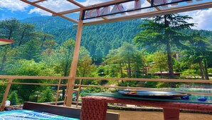 Quarto com vista para uma cadeia montanhosa arborizada, mesa de bilhar e placa com a palavra 'FAM'.