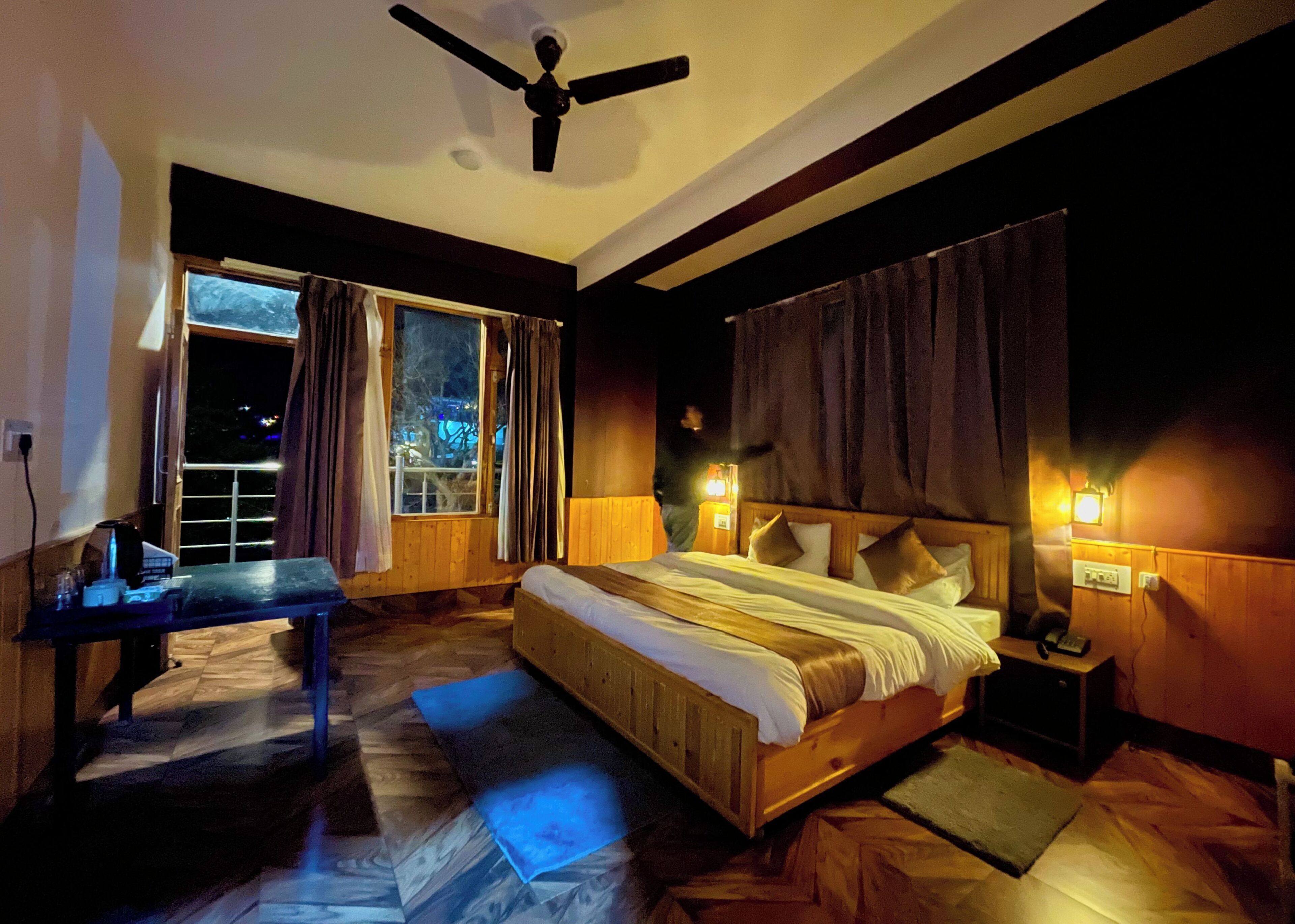 Ein Schlafzimmer mit Bett, Nachttisch, Lampe und Blick ins Freie.