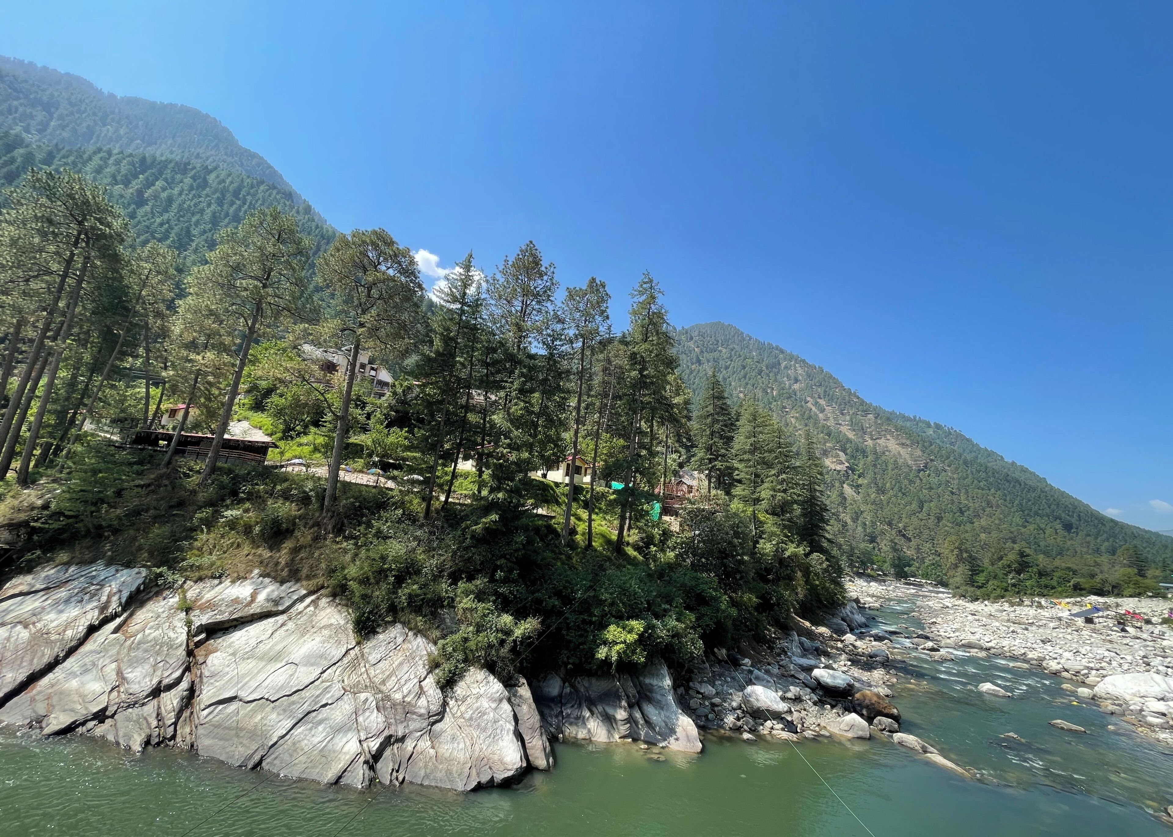 A river with rocky banks and a forested hillside.