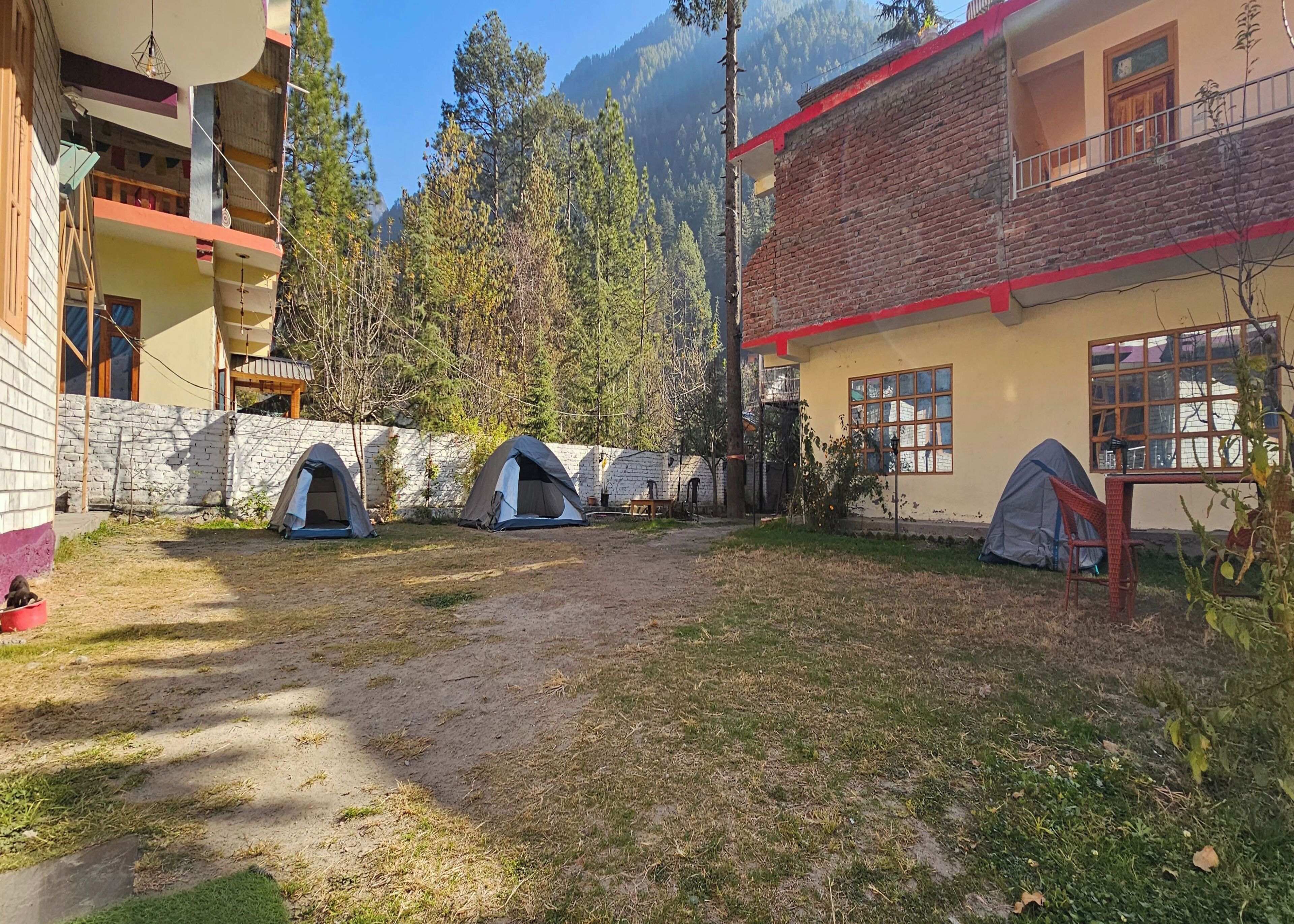 A courtyard with multiple tents, a stone wall, and a building with a balcony.