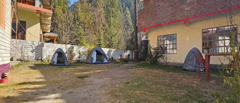 A courtyard with multiple tents, a stone wall, and a building with a balcony.