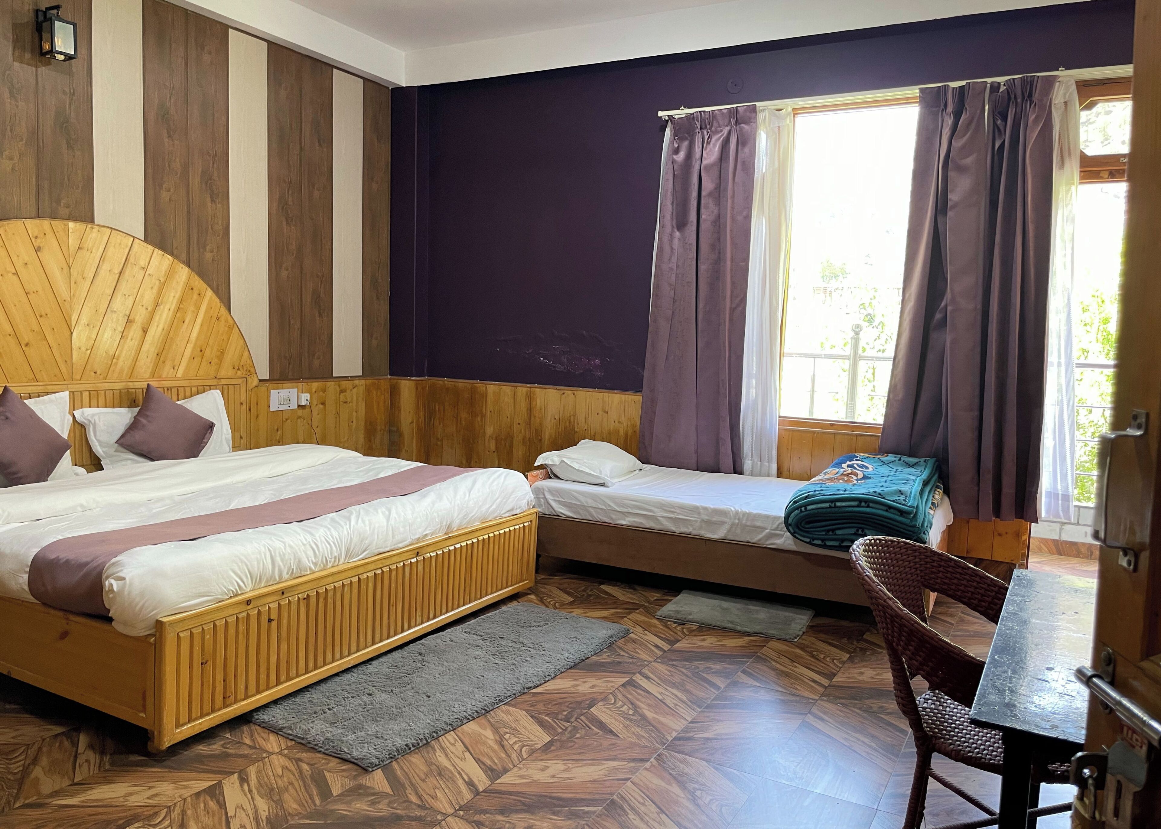 Un dormitorio con cabecera de madera, dos camas, un escritorio y una silla.