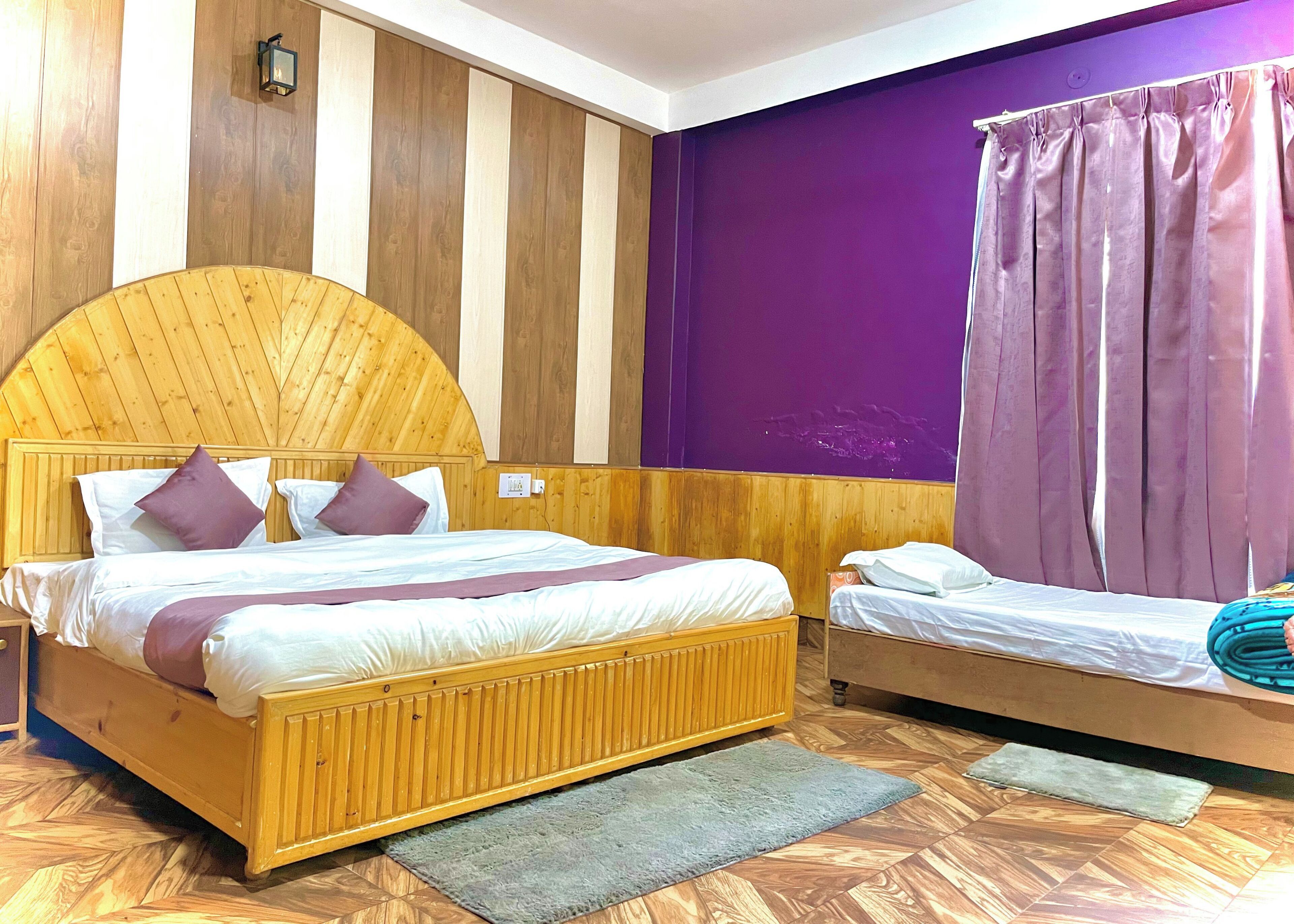 A room with a large bed, a smaller bed, and a wooden headboard.