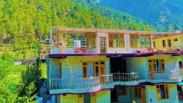 A multi-story building with balconies, a sign reading "NAP LANDS", and a mountainous backdrop.