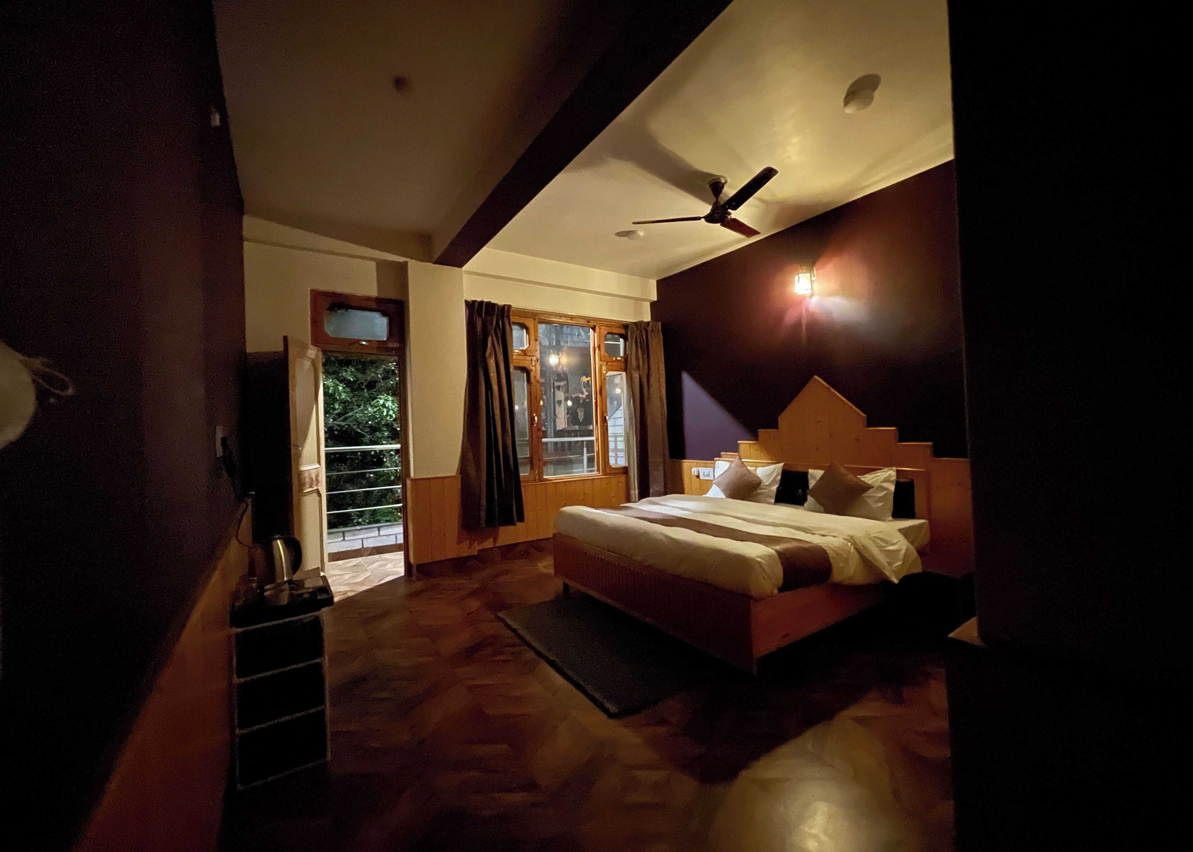 Une chambre à coucher avec un lit, un ventilateur de plafond, une fenêtre avec des rideaux et une vue sur l’extérieur.