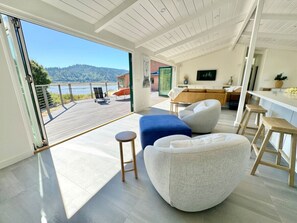 A spacious living area with a large sliding glass door leading to an outdoor deck. - Point of Views - An Absolute Gem! (Point Reyes Station)