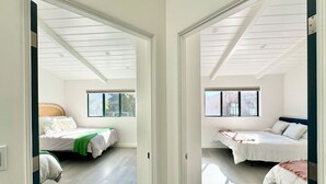Quarto com duas camas, uma janela grande e um claraboia.