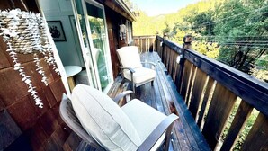 Un pontile in legno con due poltrone da relax e un'ampia vetrata che dà su una stanza.