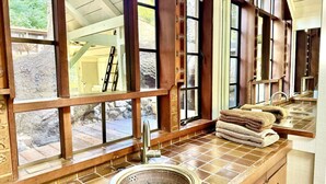 Une salle de bain avec une grande fenêtre, un lavabo et des serviettes posées sur le comptoir.