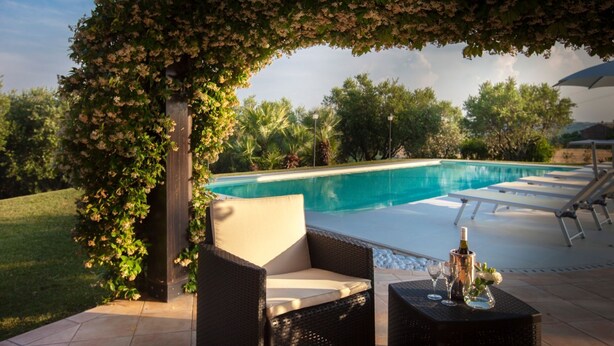 An outdoor pool area with a pergola covered in flowering vines, lounge chairs, and a table with a bottle and glasses. - Stunning villa with pool in the Marche countryside, just 10 minutes from the beaches of Senigallia (Senigallia)