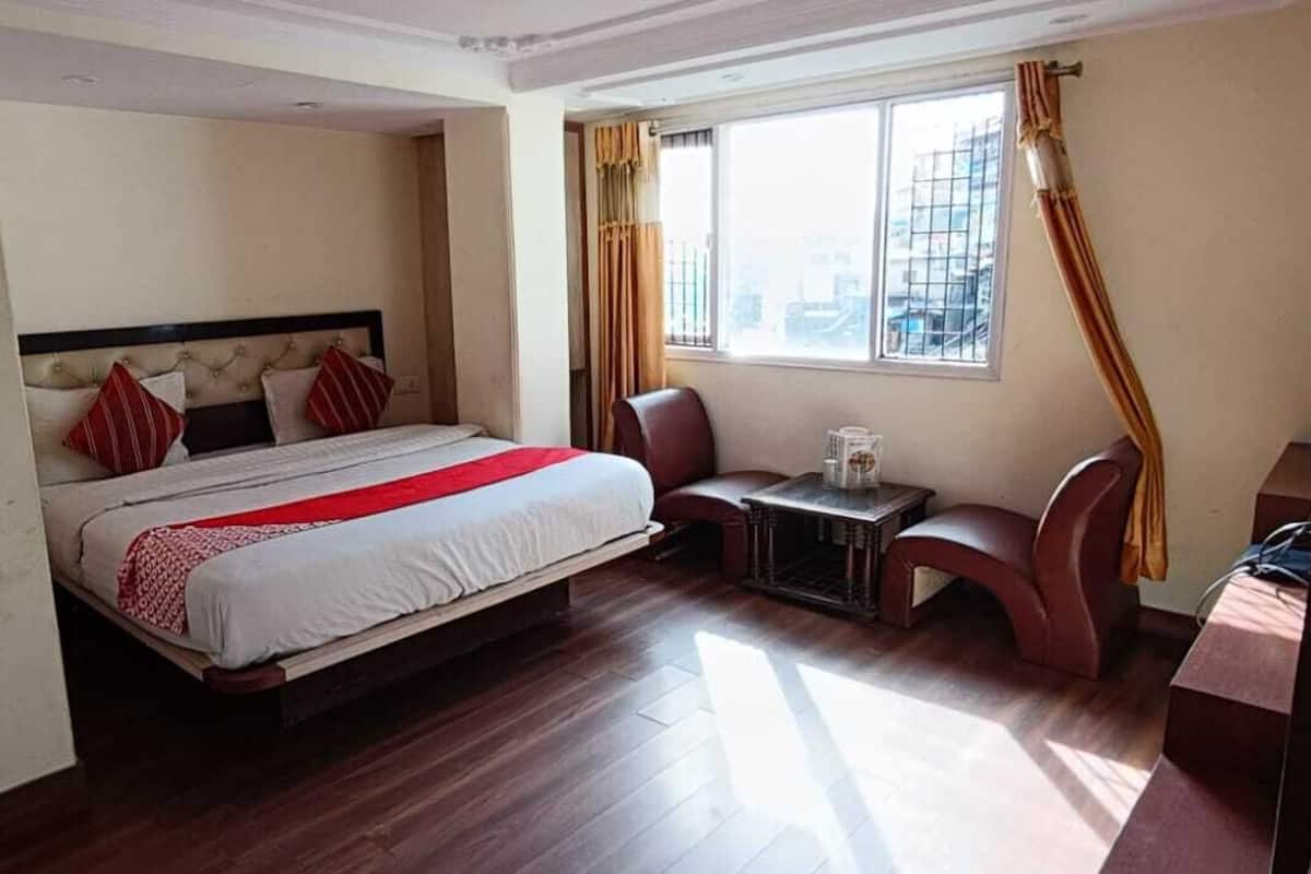 A hotel room with a bed, a small table, a chair, and a TV.