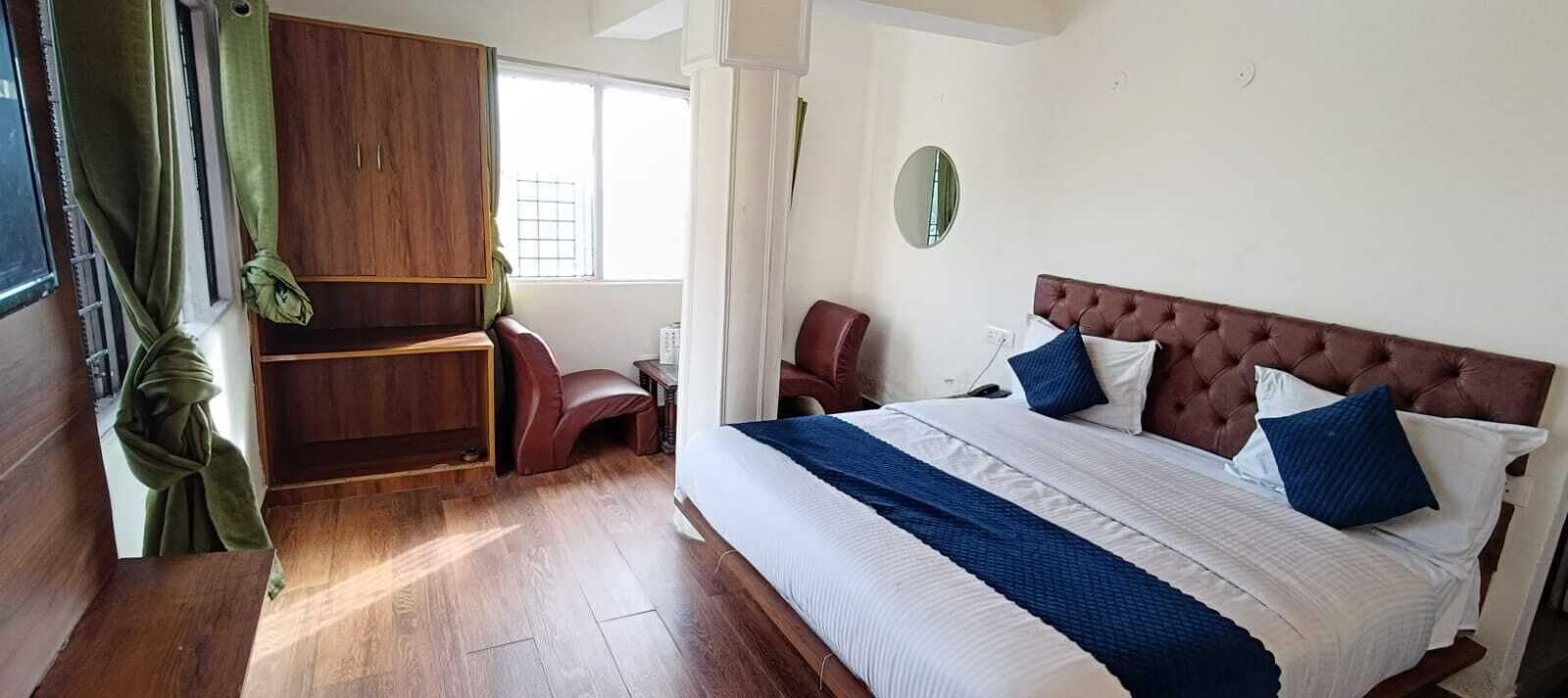 Un dormitorio con una cama grande, un armario de madera, una silla y una ventana con cortinas.