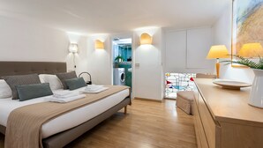 A modern hotel room with a bed, bedside lamps, a small table with a lamp, and a view of the bathroom. - Designer two-level apartment in the heart of Trastevere (Roma)