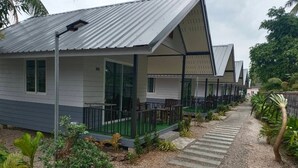 Une rangée de bâtiments modernes, de plain-pied, dotés d’espaces extérieurs aménagés pour s’asseoir et d’un chemin de gravier.