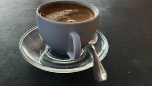 Une tasse de café sur une table, avec vue sur la mer et une plage en arrière-plan.
