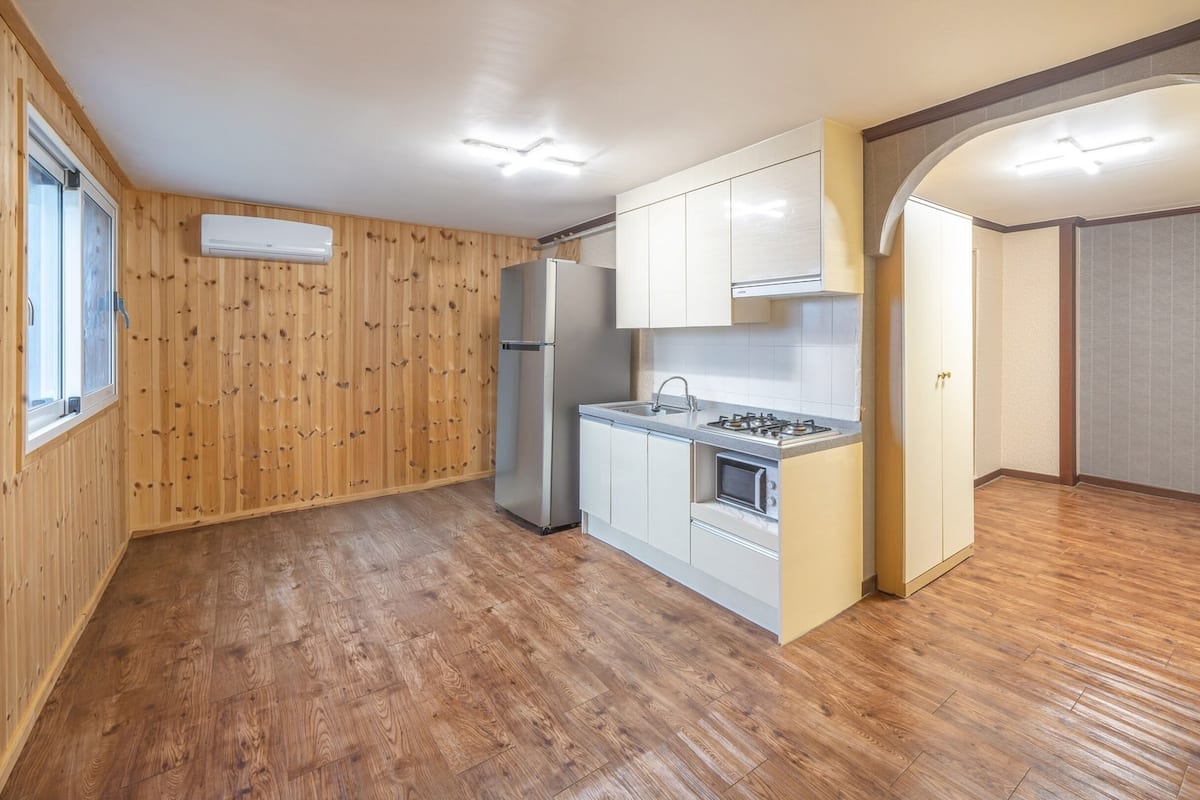 Une cuisine de taille réduite avec des murs en bois, un réfrigérateur, une cuisinière et un évier.