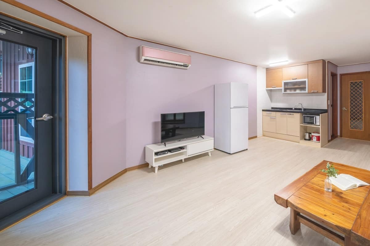 Un espace de vie compact comprenant une kitchenette, un coin repas et un téléviseur.