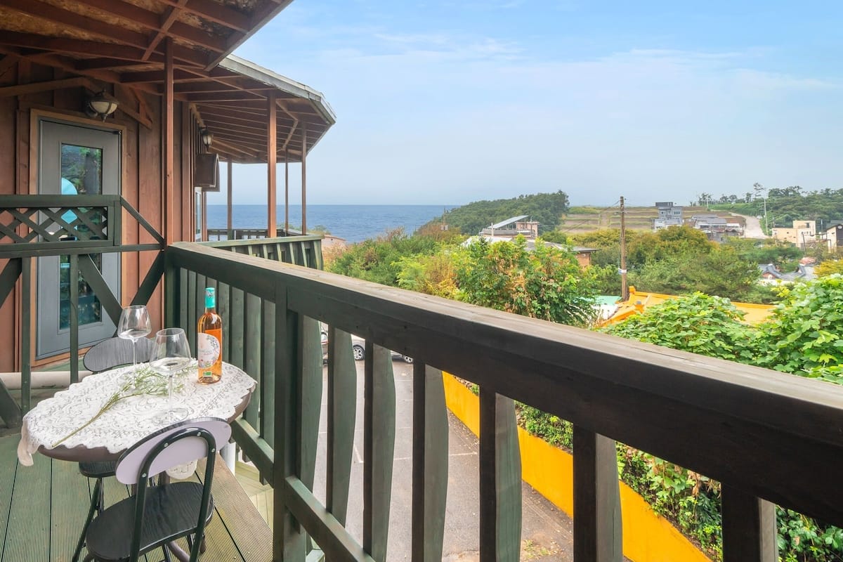 Une terrasse en bois avec une table et des chaises, offrant une vue sur la côte.