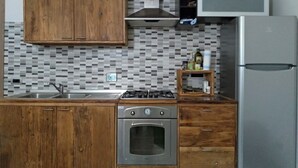 Une cuisine avec des meubles de rangement en bois, une cuisinière à gaz, un four, un four à micro-ondes et un réfrigérateur.