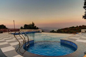 A swimming pool with a checkered floor, surrounded by a low wall and a view of distant hills. - Royal Resort (Mahabaleshwar)