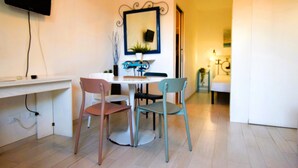 Un comedor con una mesa redonda, dos sillas, un televisor en la pared y un espejo.