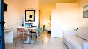 Una sala de estar moderna con un sofá blanco, una mesa de comedor con sillas y un televisor montado en la pared.