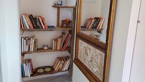 A room with a bookshelf filled with books and a decorative mirror with a gold frame. - Casa Luisa  1 - Casa Luisa 1 (Marciana)