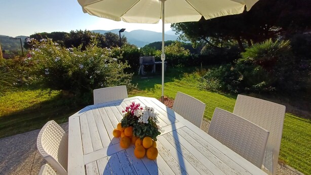 An outdoor dining area with a white table and chairs, an umbrella, and a flower arrangement. - Casa Luisa  1 - Casa Luisa 1 (Marciana)
