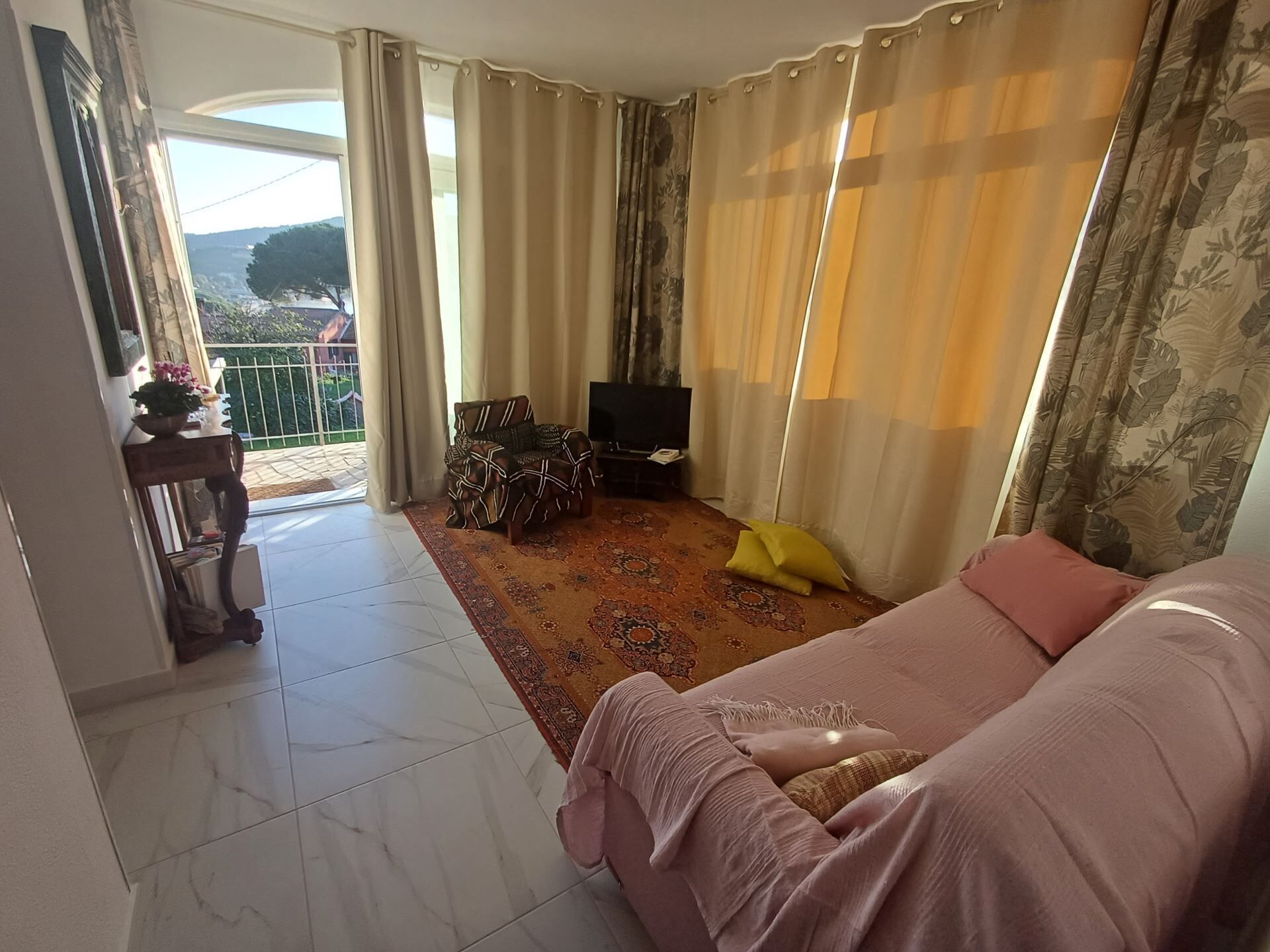 Olohuone, jossa on sohva, televisio ja kuviollinen matto.