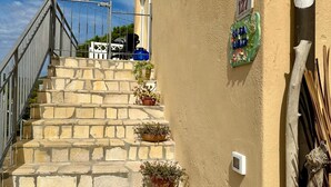 A stone staircase leading up to a building with a number 127 sign, potted plants, and a rustic wooden fence.